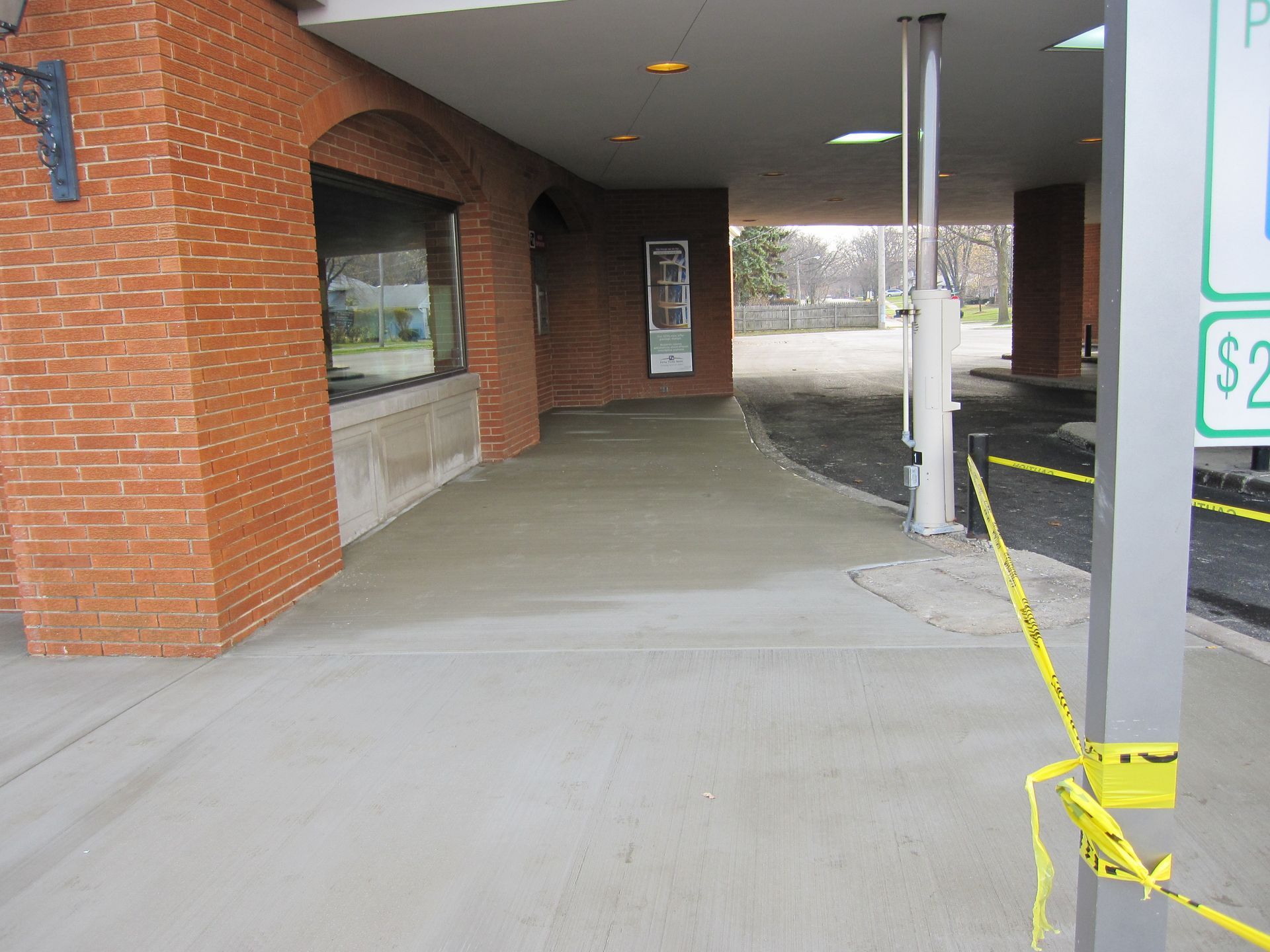 Exterior of building with new concrete; caution tape across path.