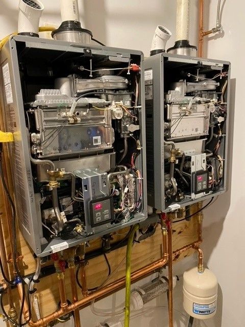 Two wall-mounted, opened water heaters with copper pipes, connected to the plumbing.