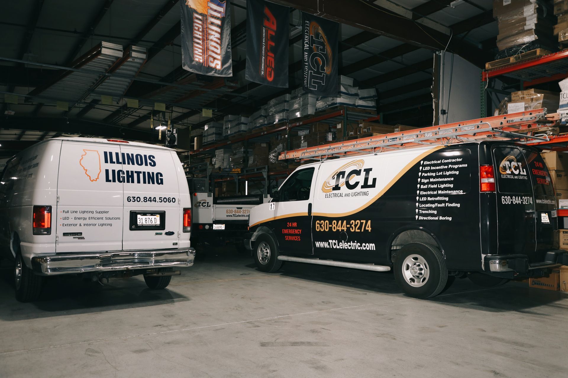 Two work vans parked in a warehouse. One is white with 