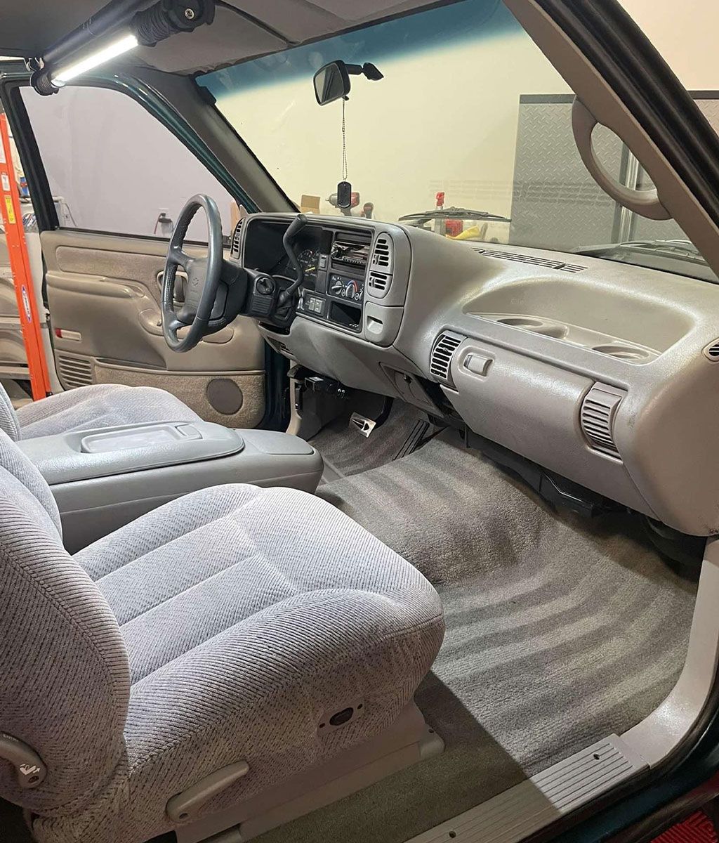 Interior view of a light gray pickup truck cab, with seats, dashboard, and steering wheel.