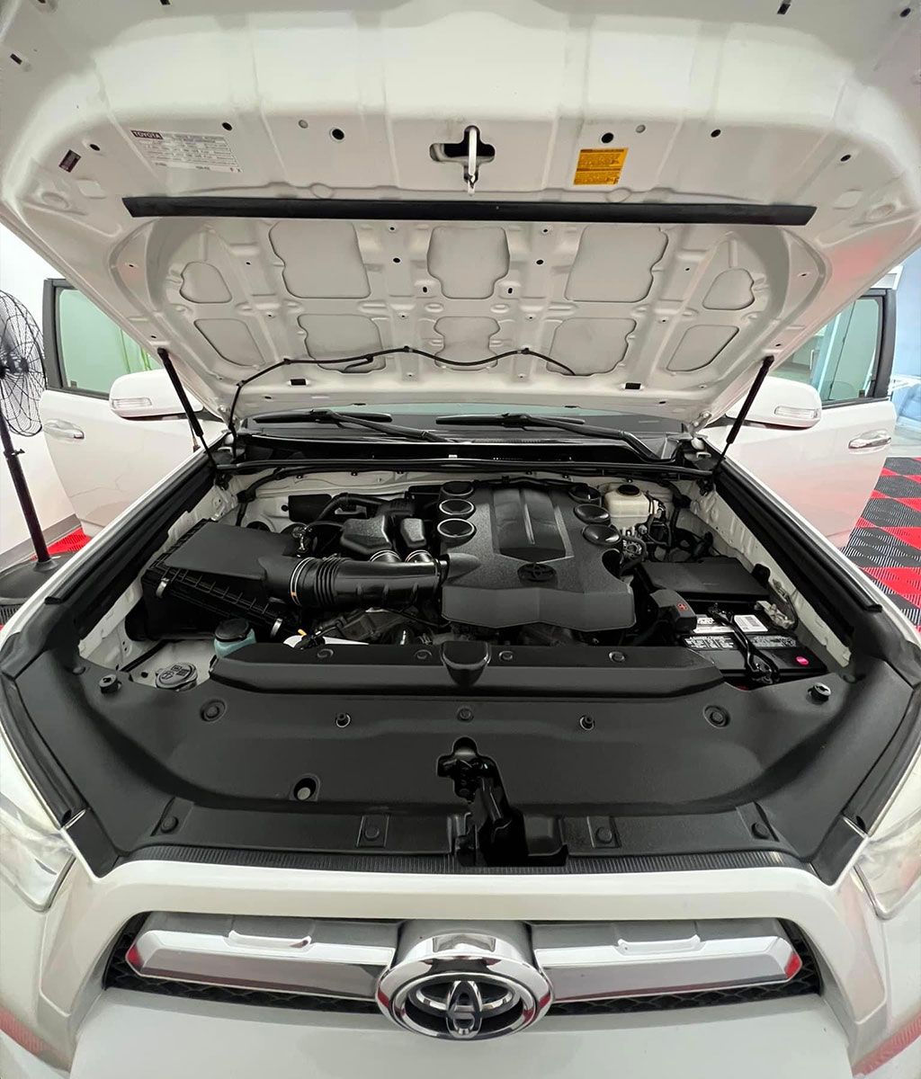 White Toyota SUV with hood open, engine bay visible.