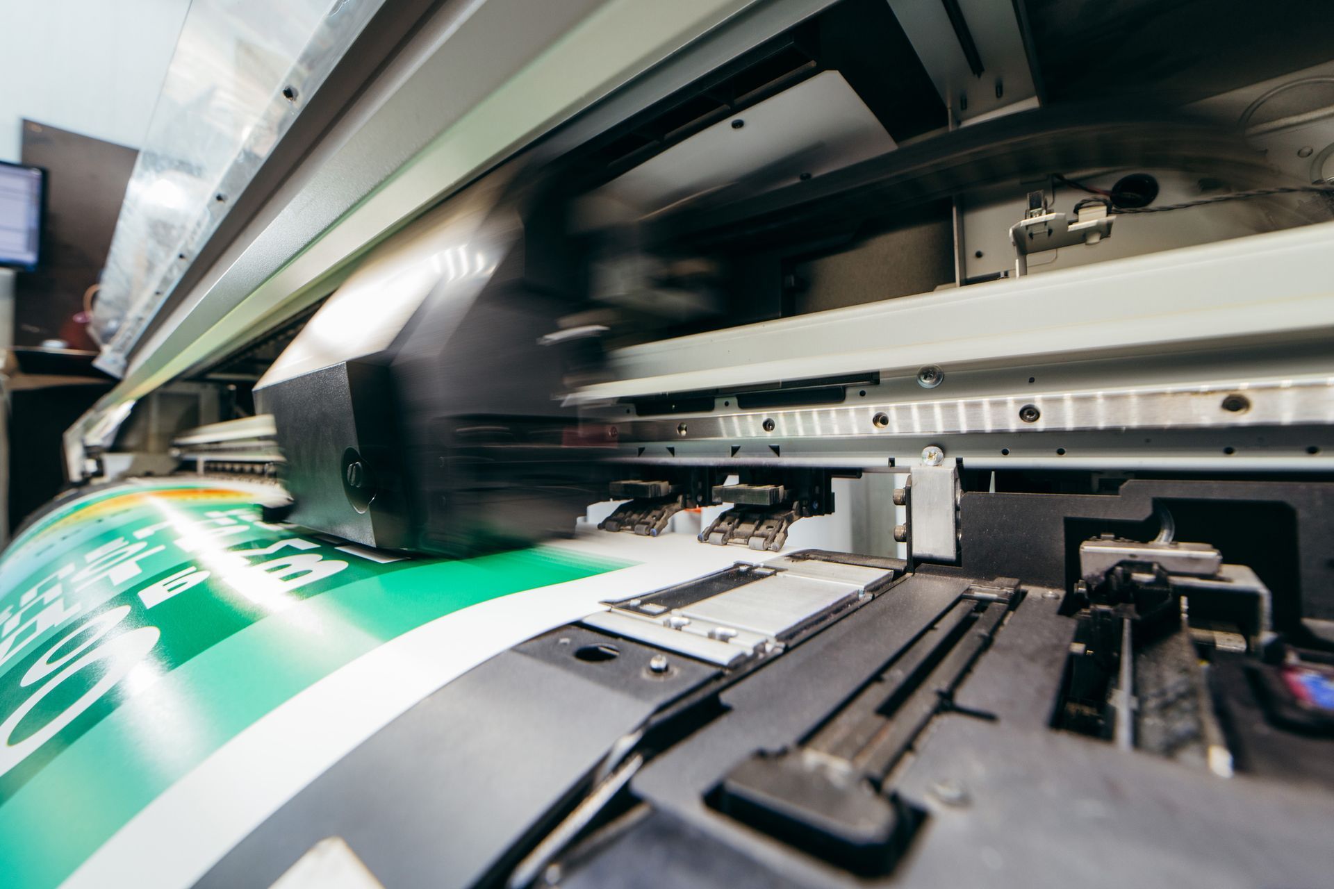 Large-format printer in action, printing a green and white graphic.