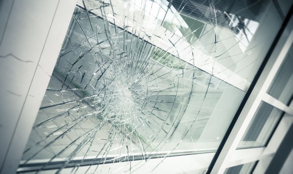 Broken windowpane with radiating cracks; outside view visible.