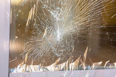 Shattered glass with a spiderweb-like pattern of cracks, possibly on a window or display.