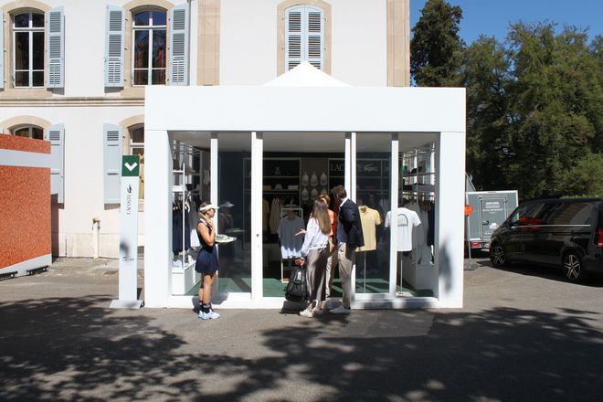 Par une journée ensoleillée, des gens étaient rassemblés devant une entrée blanche ressemblant à un pavillon
