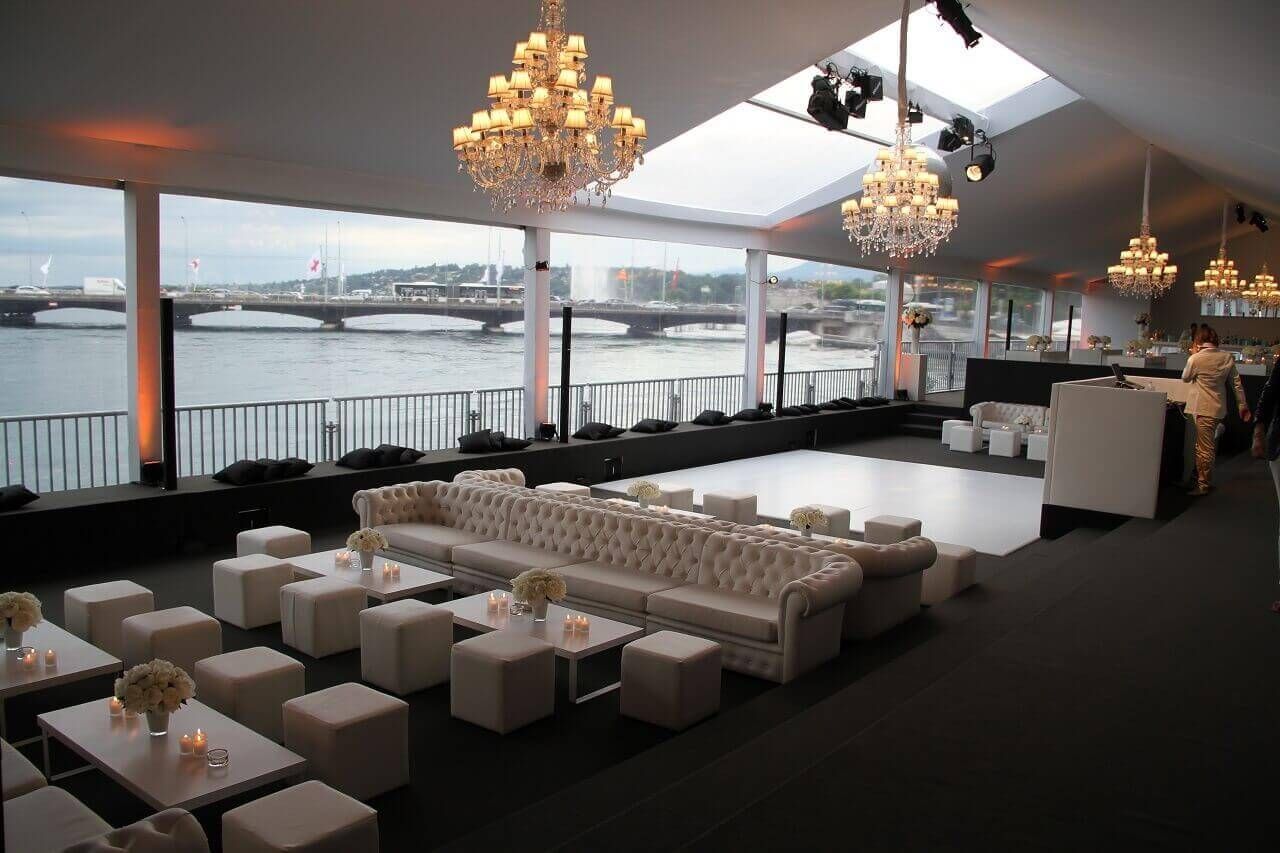 Salon événementiel intérieur élégant avec canapés blancs et lustres donnant sur l'eau