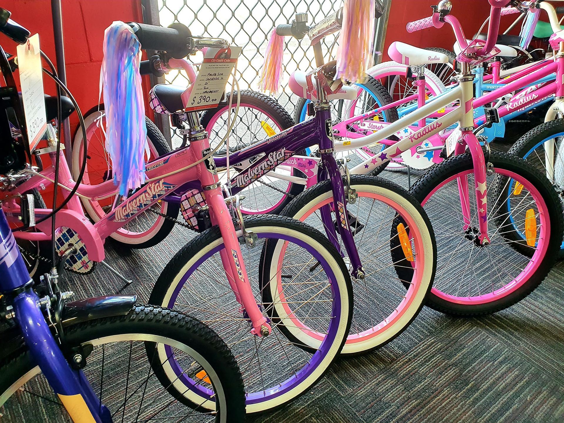 Row of colourful children's bicycles with streamers, displayed in a store — City Centre Cycles in Berserker, QLD