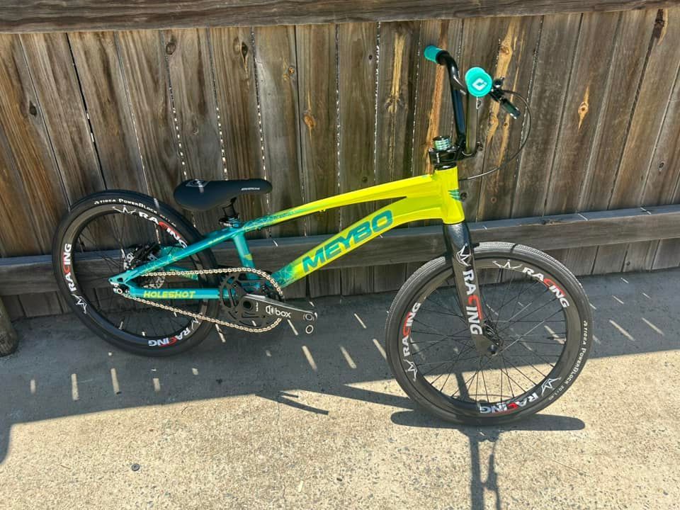 Lime Green and Teal Bmx Bike with Black Tires Against a Wooden Fence — City Centre Cycles in Berserker, QLD