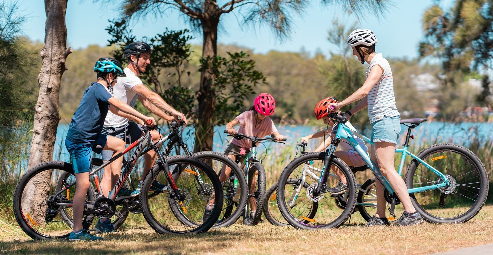 Four Cyclists with Helmets Pause on A Sunny Dirt Trail in A Wooded Park — City Centre Cycles in Berserker, QLD
