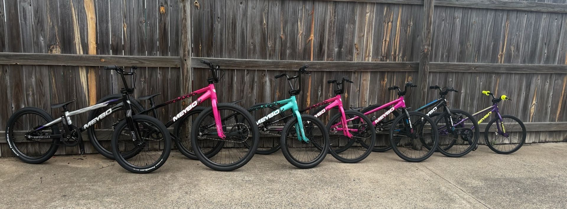 Four Bicycles Lined up Against a Wooden Fence — City Centre Cycles in Berserker, QLD