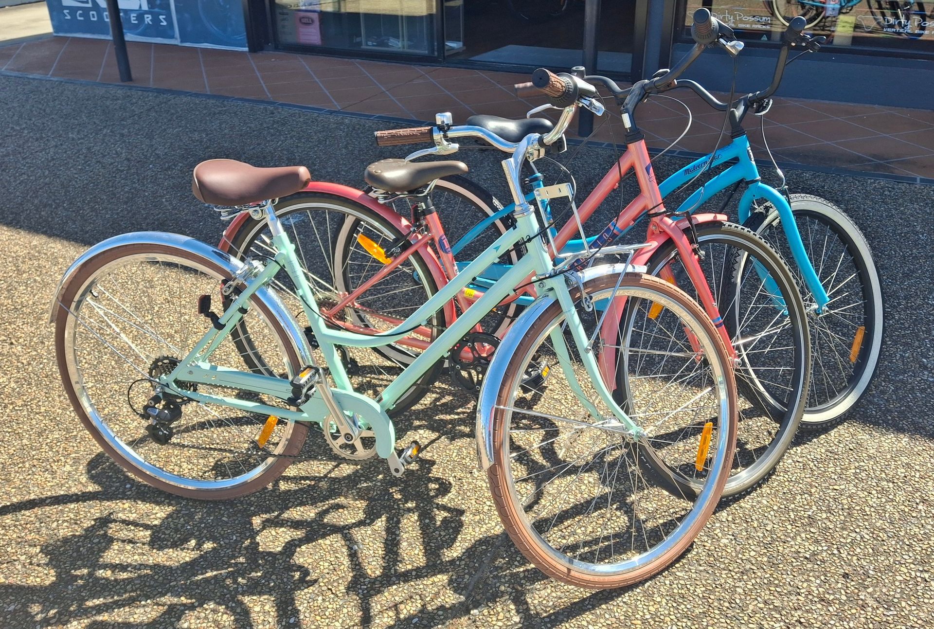 Several colourful bicycles parked together on a sunny gravel lot — City Centre Cycles in Berserker, QLD