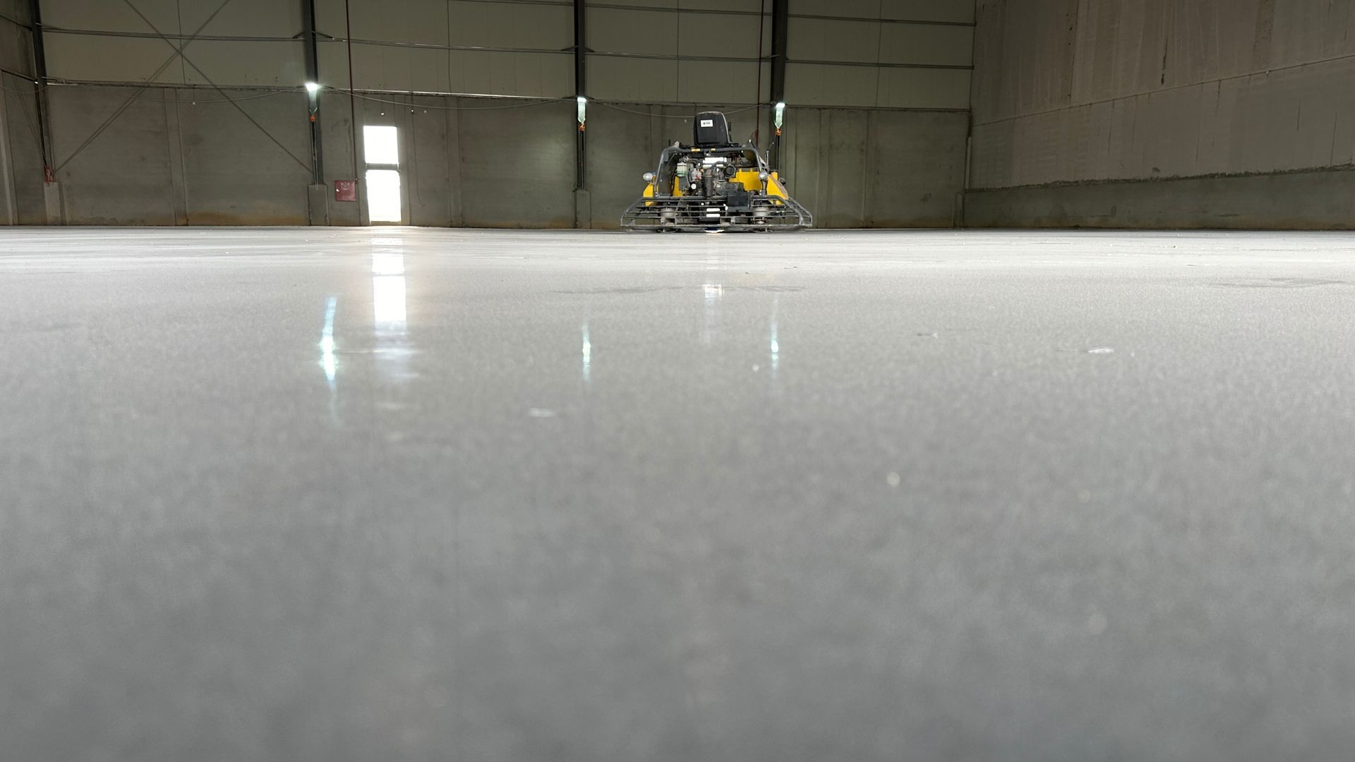 Polished concrete floor being cleaned by a machine inside a large warehouse. Polished concrete floor being cleaned by a machine inside a large warehouse.