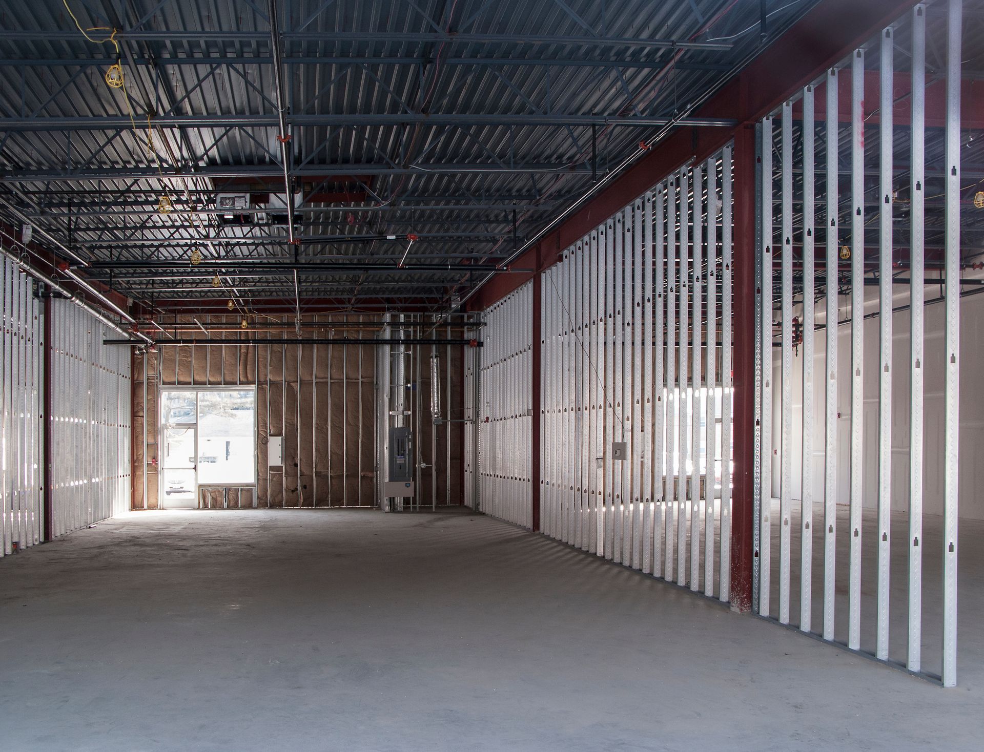 Interior of a building under construction, showing metal framing and concrete floor.