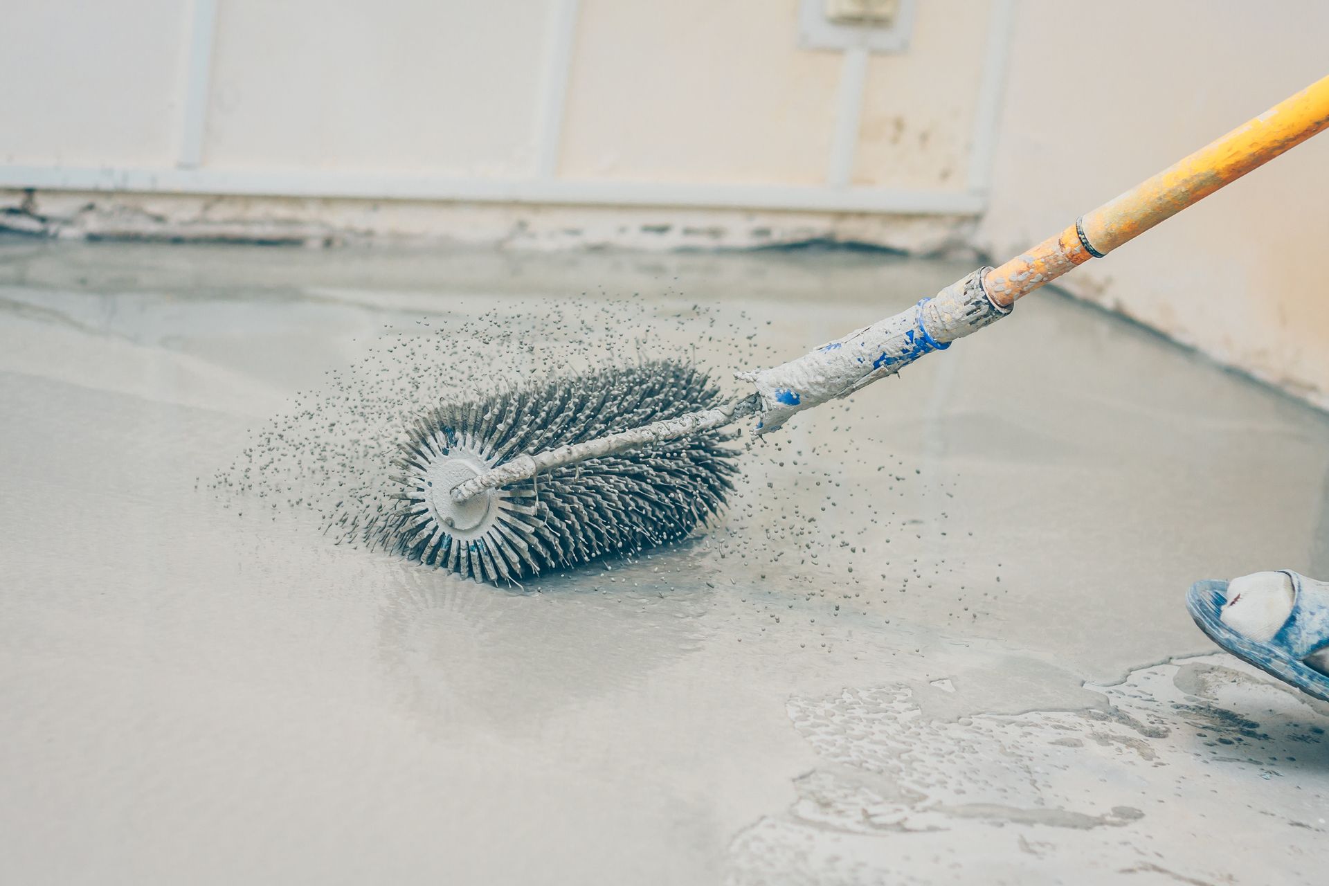Person using a spiked roller to level wet concrete flooring. Person using a spiked roller to level wet concrete flooring.