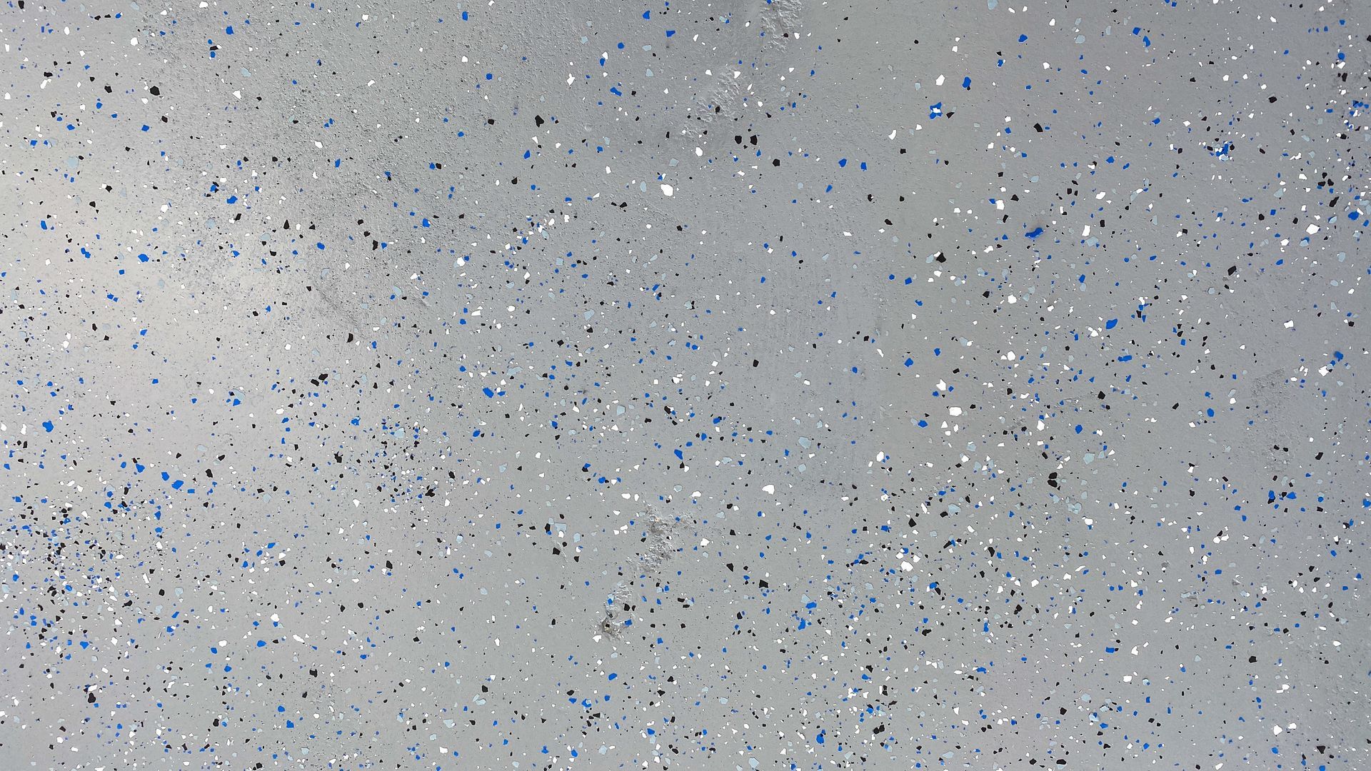 Gray speckled floor with black, blue, and silver flecks. Gray speckled floor with black, blue, and silver flecks.