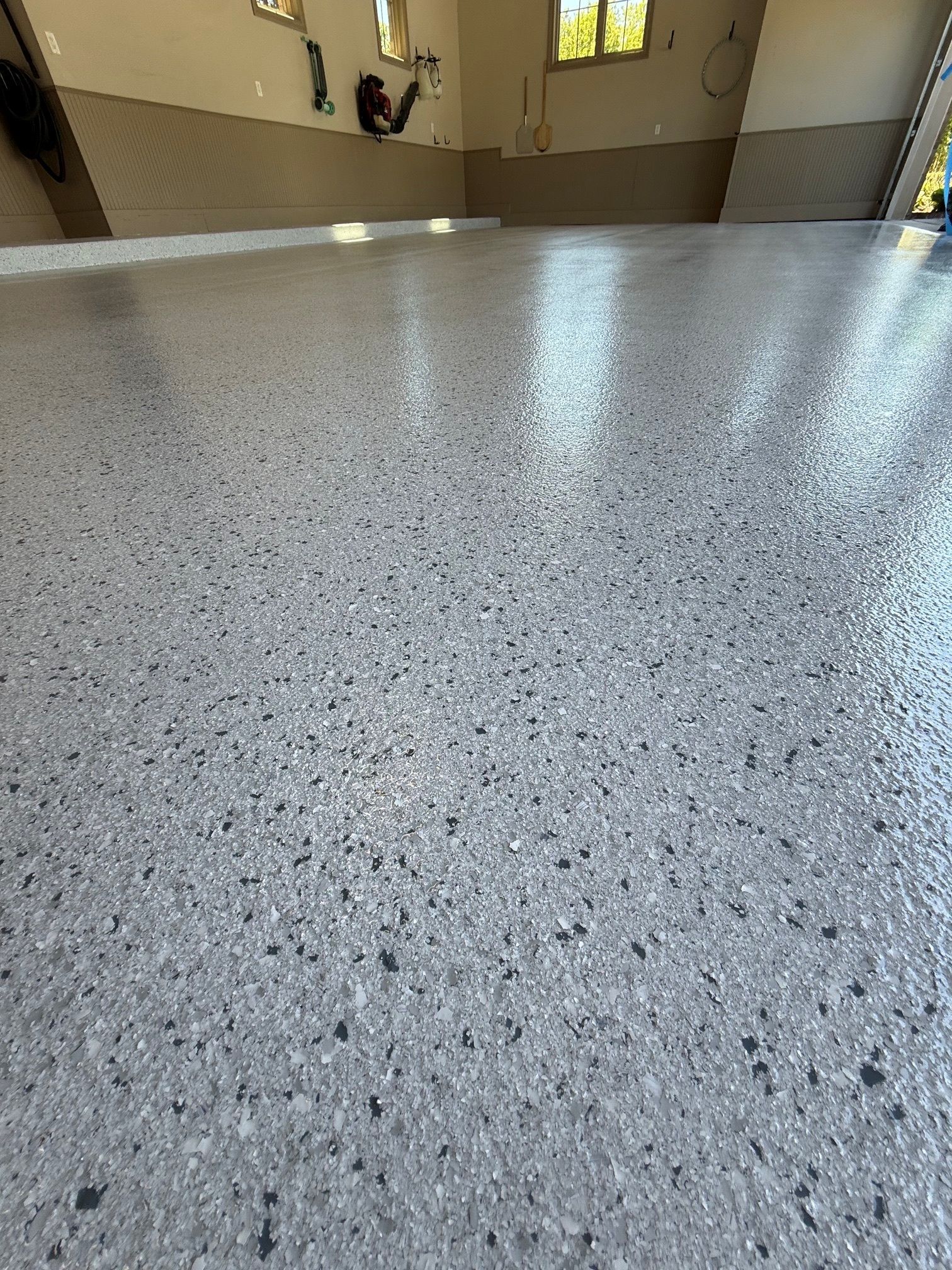 Speckled light gray epoxy floor in a room with windows and wall sconces.
