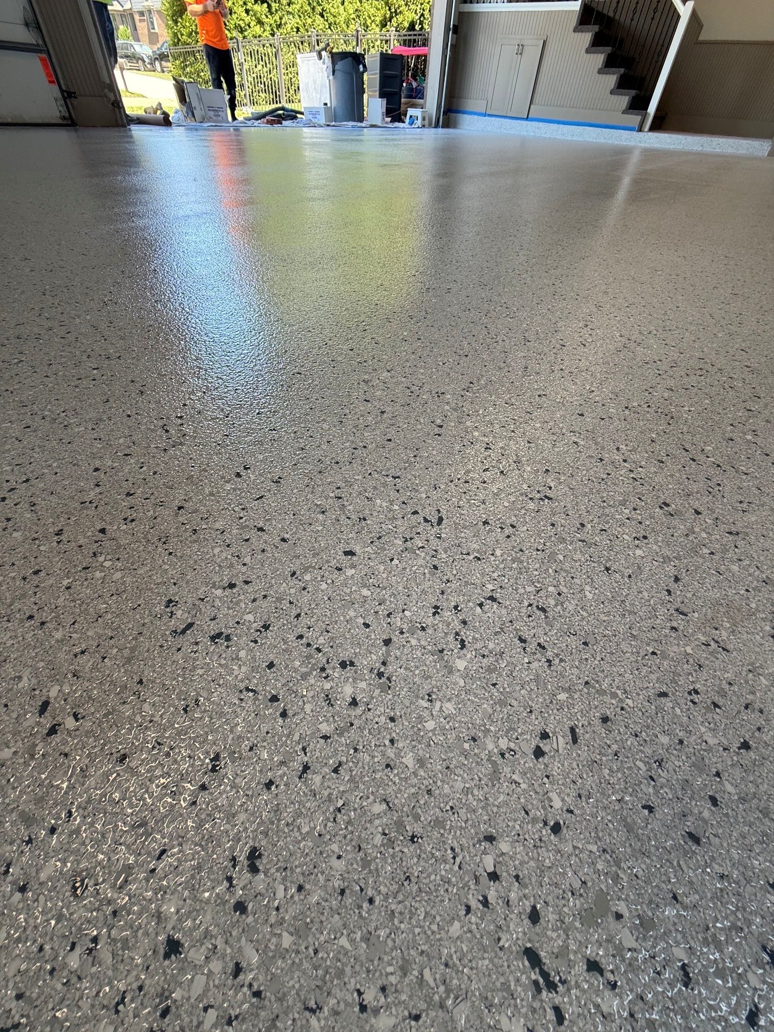 Speckled gray terrazzo floor in a lobby with stairs and glass entrance visible in the background