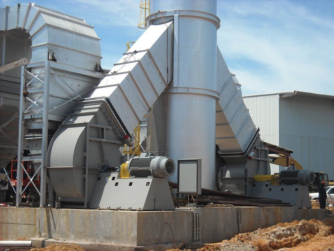 Industrial ventilation system with a large fan, ductwork, and smokestack on a concrete base outdoors.