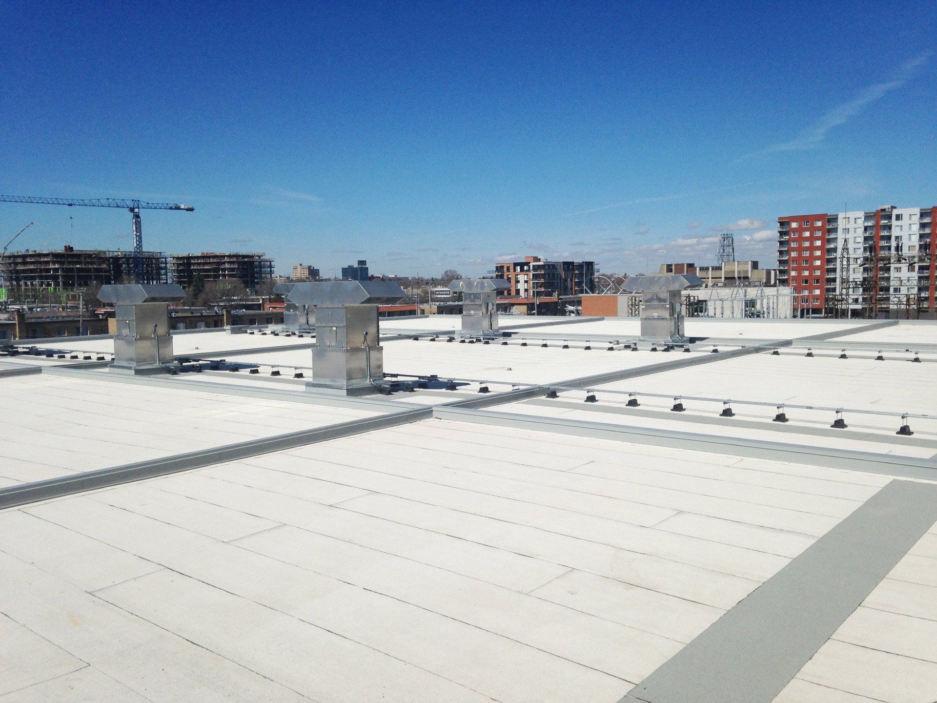 View from a rooftop, showing ventilation stacks and a cityscape on a clear, sunny day.