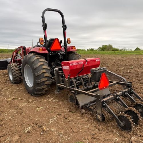 Red tractor seeding soil for prairie establishment in Southwest Wisconsin.