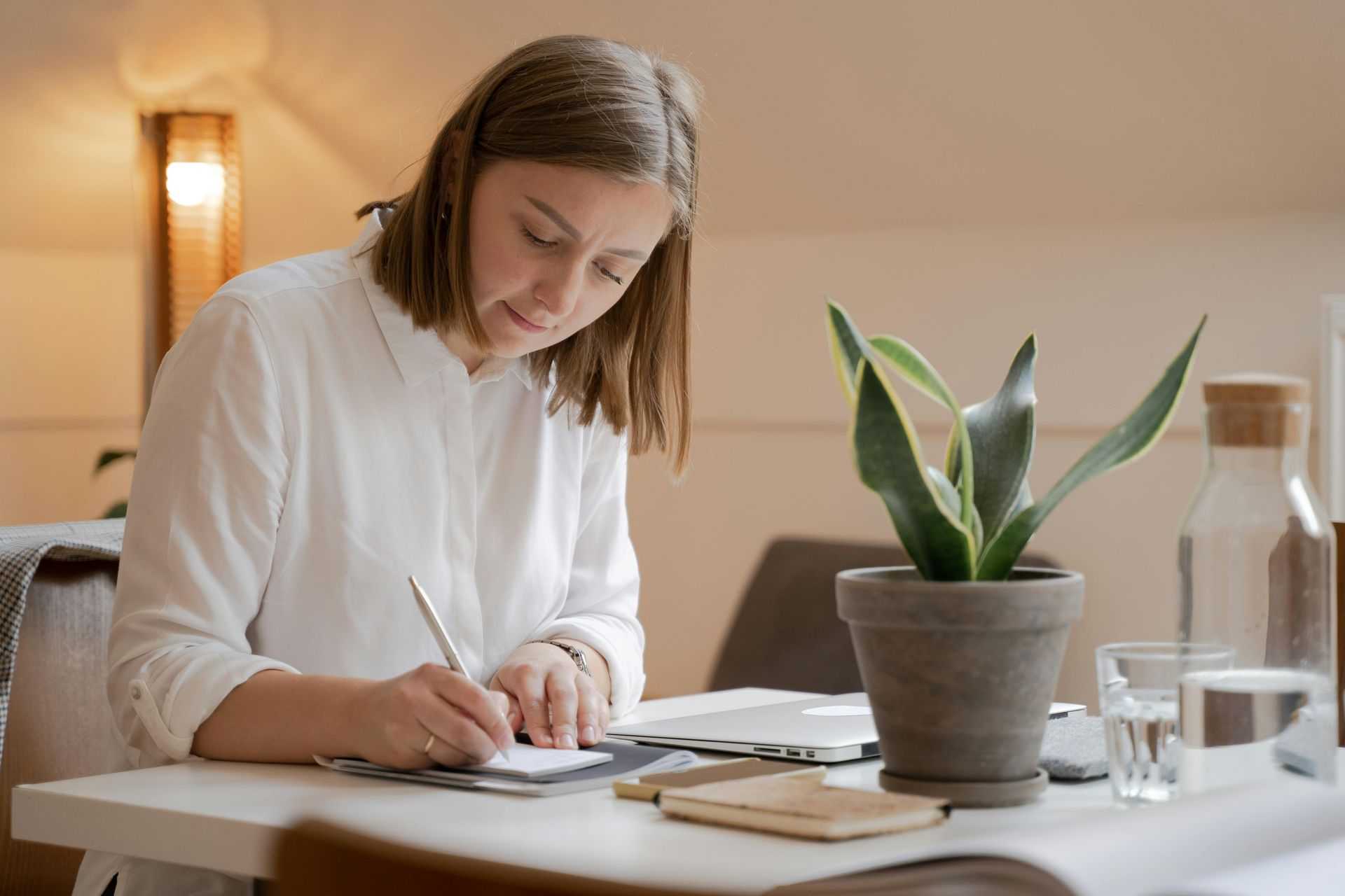 A Virtual Assistant is sitting at a table writing on a piece of paper.