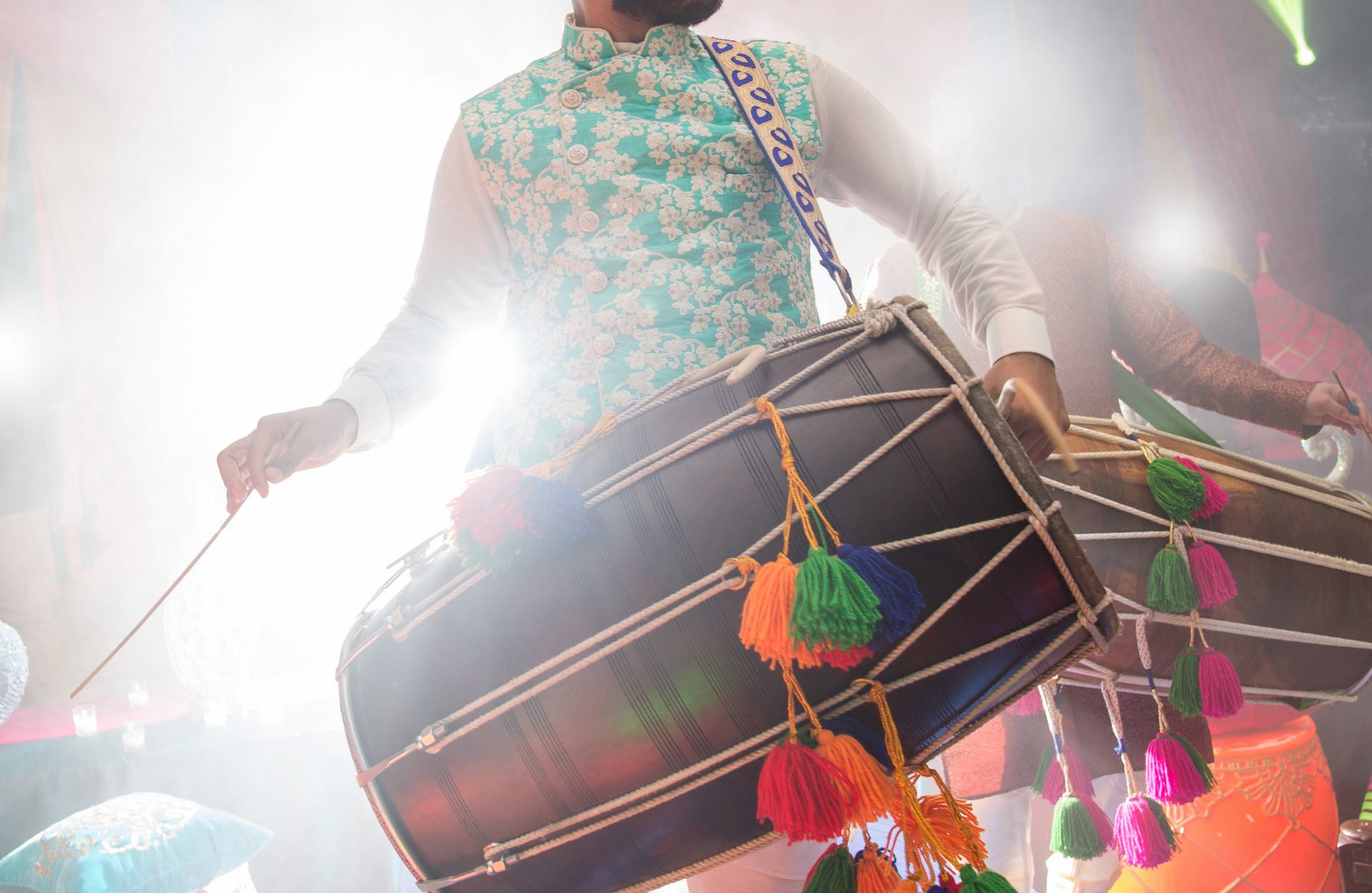 A man is playing a drum with a stick on a stage.