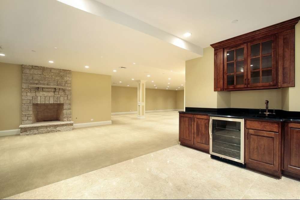 Finished basement with fireplace, bar, and beige carpet.
