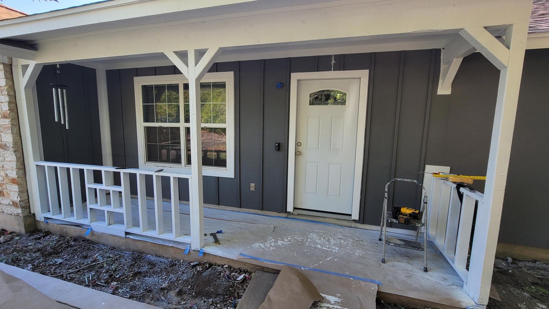 Porch with white railing, trim, and door. Gray siding.