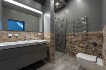 Modern bathroom with white tub, glass shower, and marble-look tile.