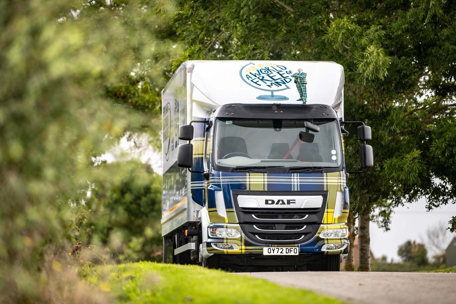 White delivery truck driving on a tree-lined road