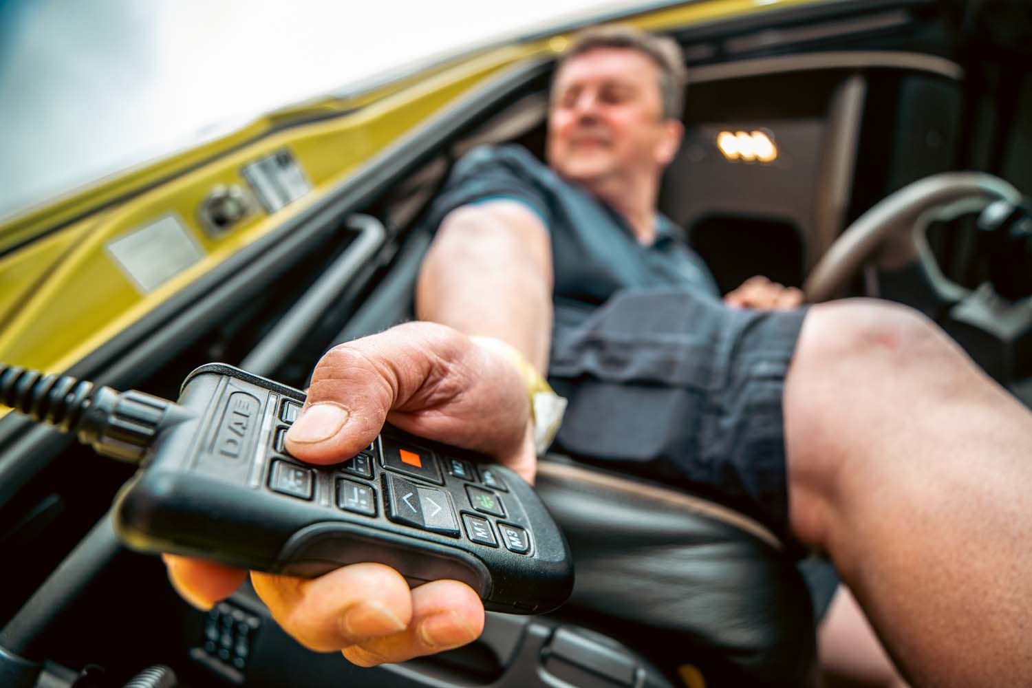 Close-up truck photography of man pushing remote button while sitting in a vehicle with the door open