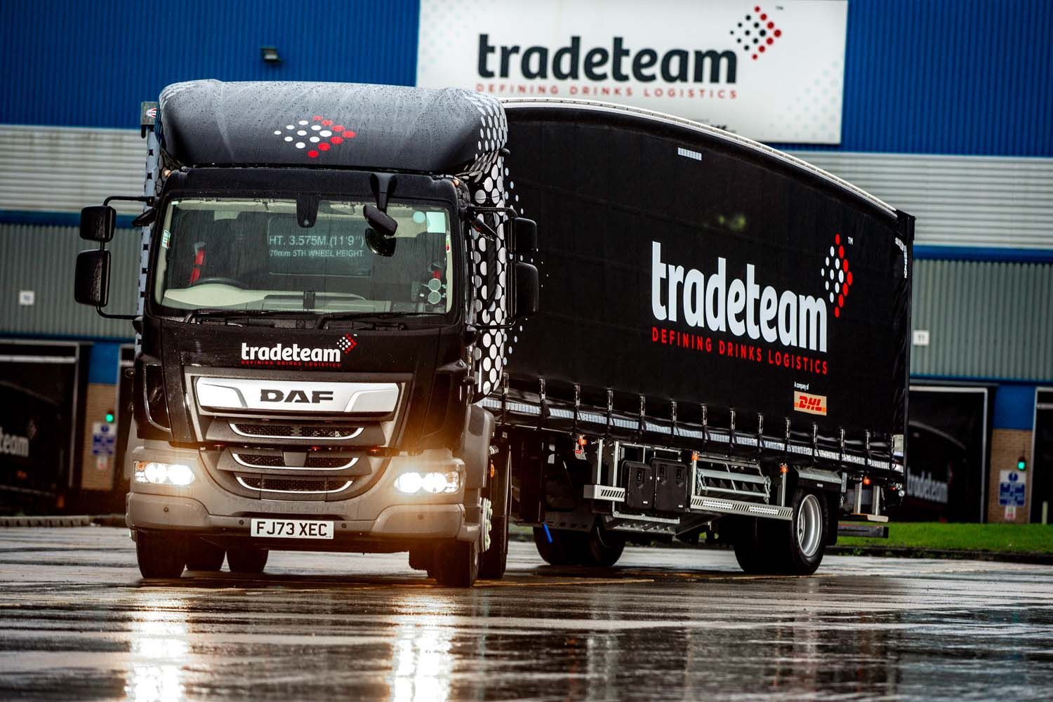 White tradeteam truck parked on a wet road outside a warehouse on a rainy day