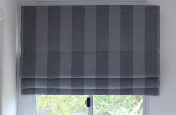 A Gray and White Striped Roman Shade Is Hanging on A Window — Bay Blinds & Doors in Bateau Bay, NSW