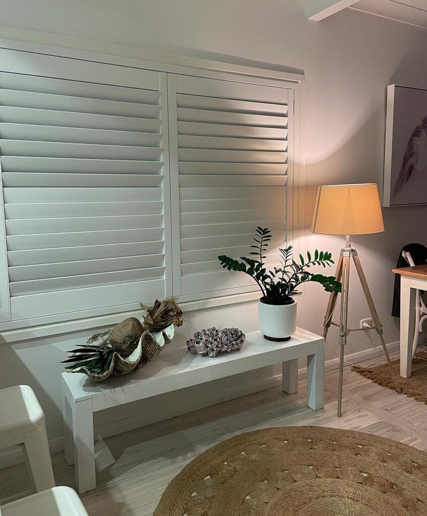 A White Car Is Parked in Front of A White Building with Shutters on It — Bay Blinds & Doors in Bateau Bay, NSW