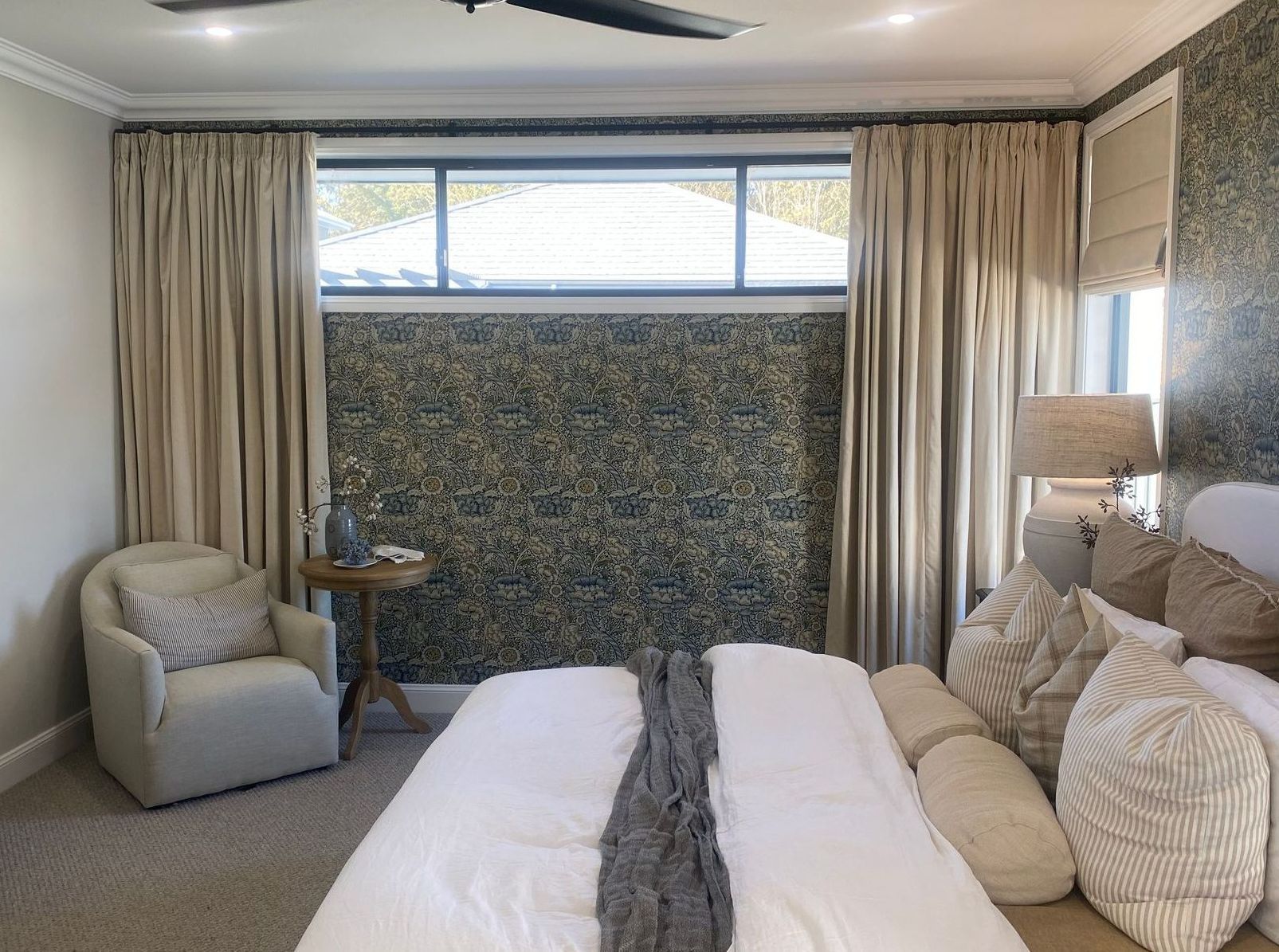 Bright bedroom with a bed, armchair, window seat, and patterned accent wall