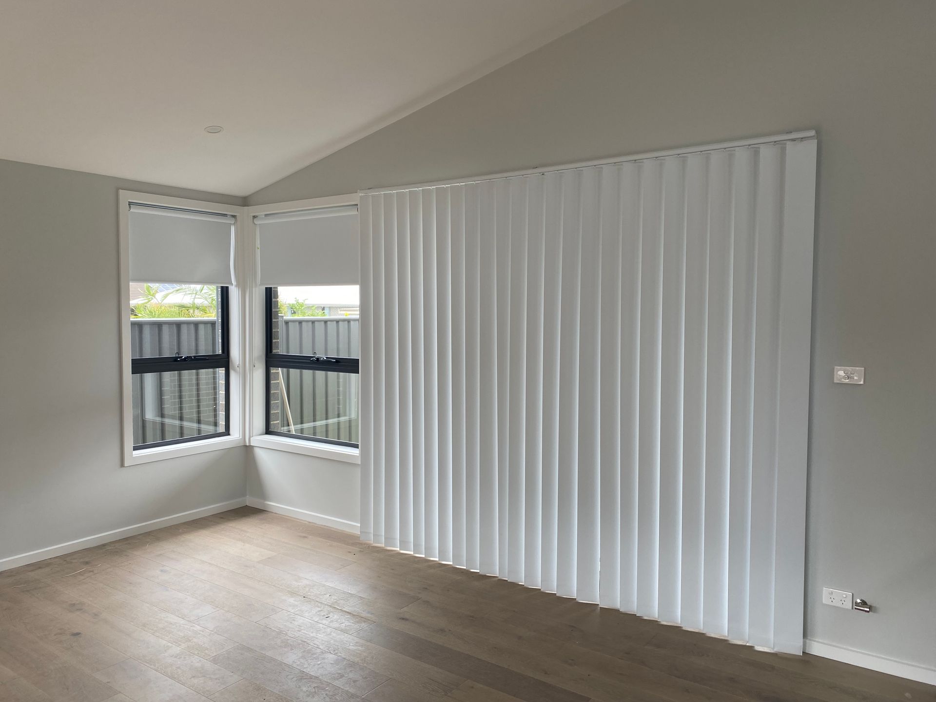 A Gray and White Striped Roman Shade Is Hanging on A Window — Bay Blinds & Doors in Bateau Bay, NSW
