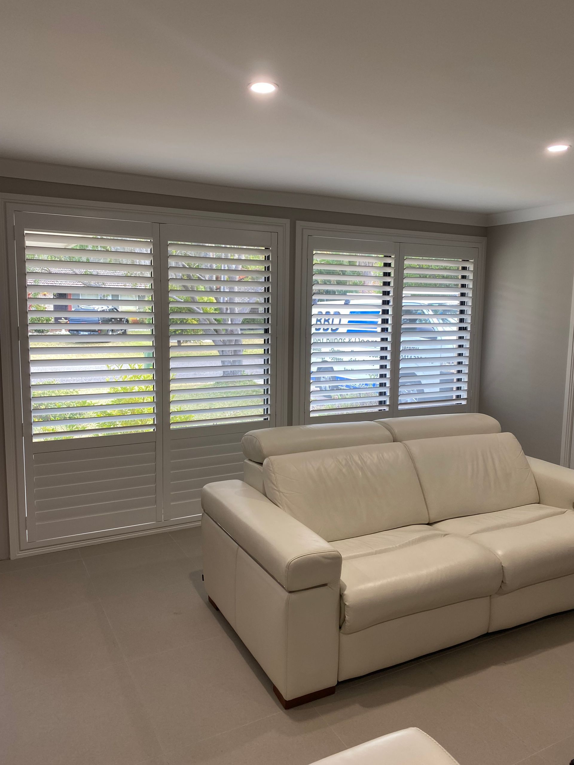 A Balcony with A Couch and Pillows and Shutters on The Windows — Bay Blinds & Doors in Bateau Bay, NSW