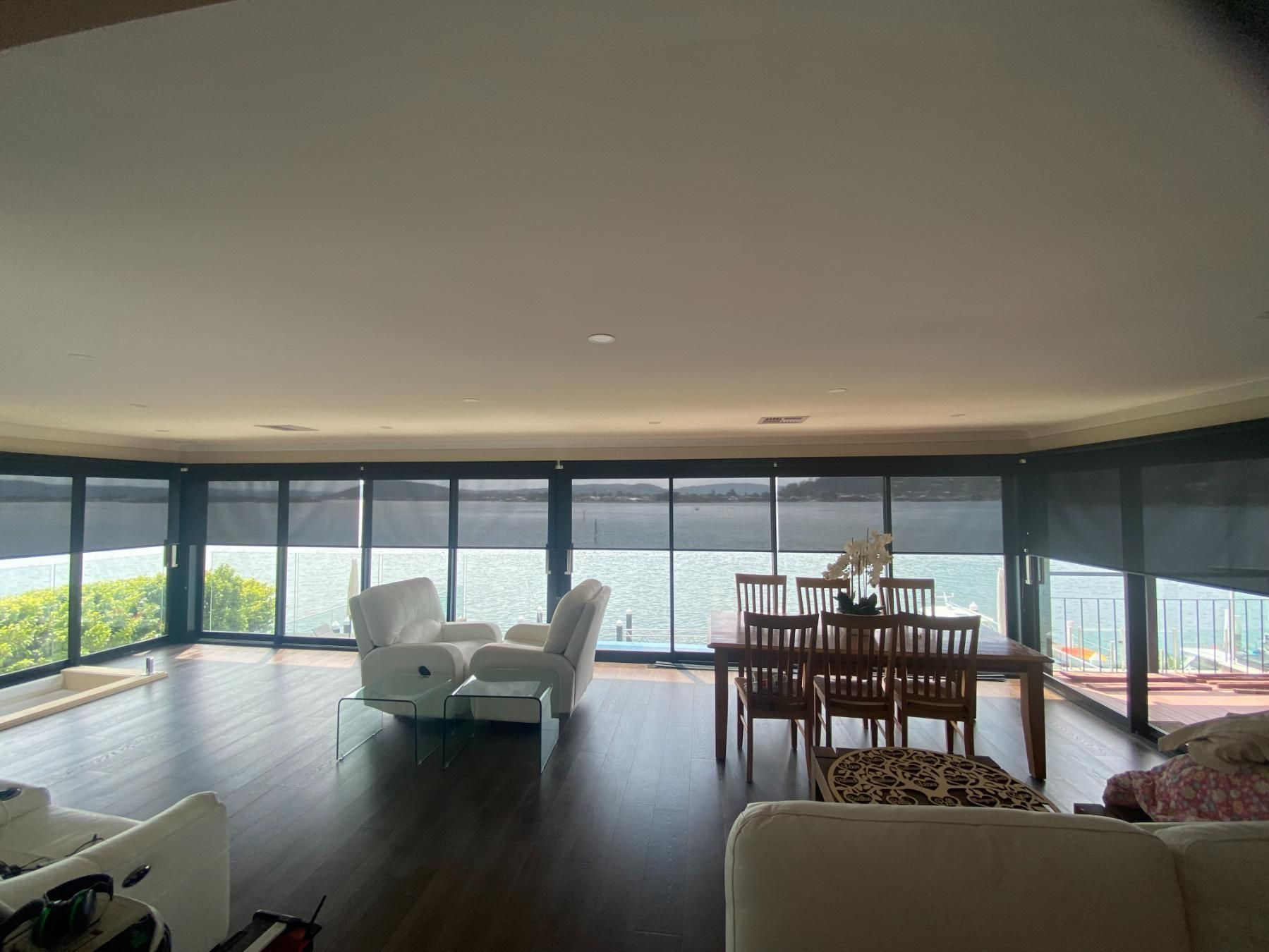 A Living Room with A Dining Table and Chairs and A View of The Water — Bay Blinds & Doors in Bateau Bay, NSW