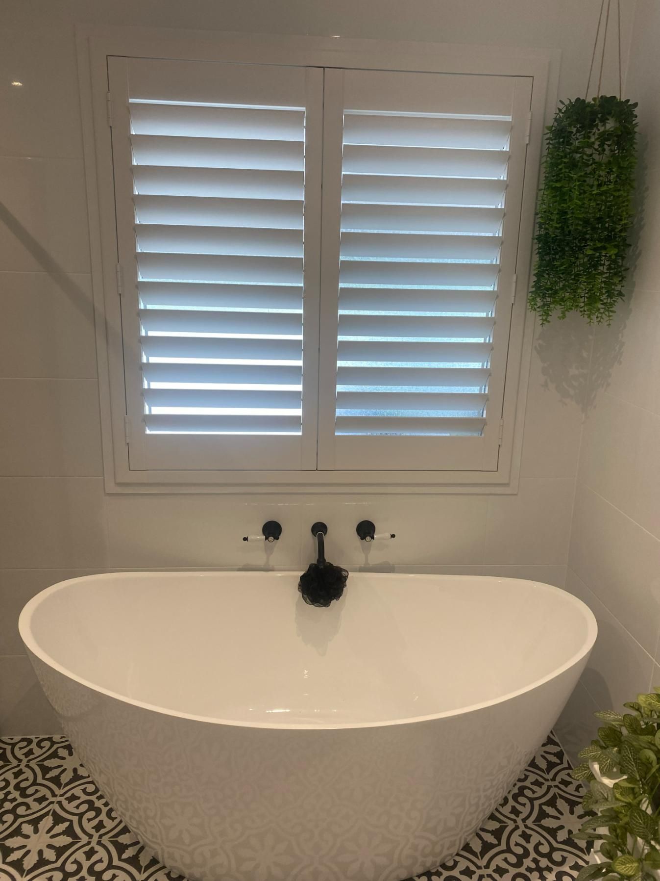 There Is a Bathtub in The Bathroom with Shutters on The Window — Bay Blinds & Doors in Bateau Bay, NSW