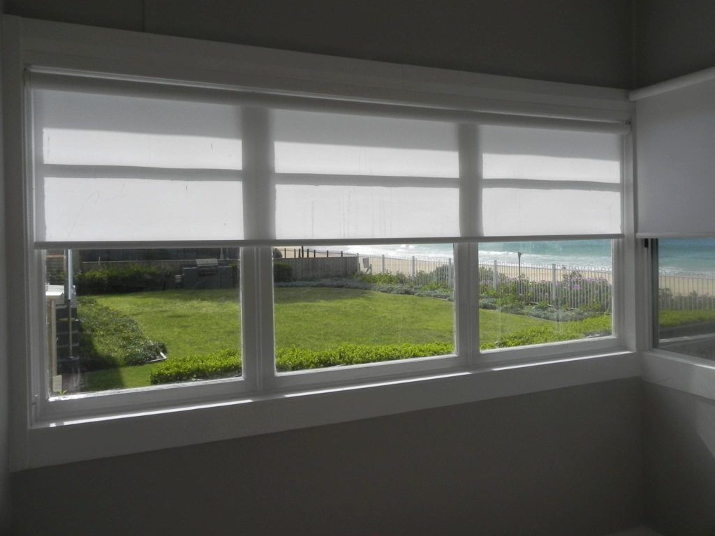 A Window with White Blinds and A View of The Beach — Bay Blinds & Doors in Bateau Bay, NSW