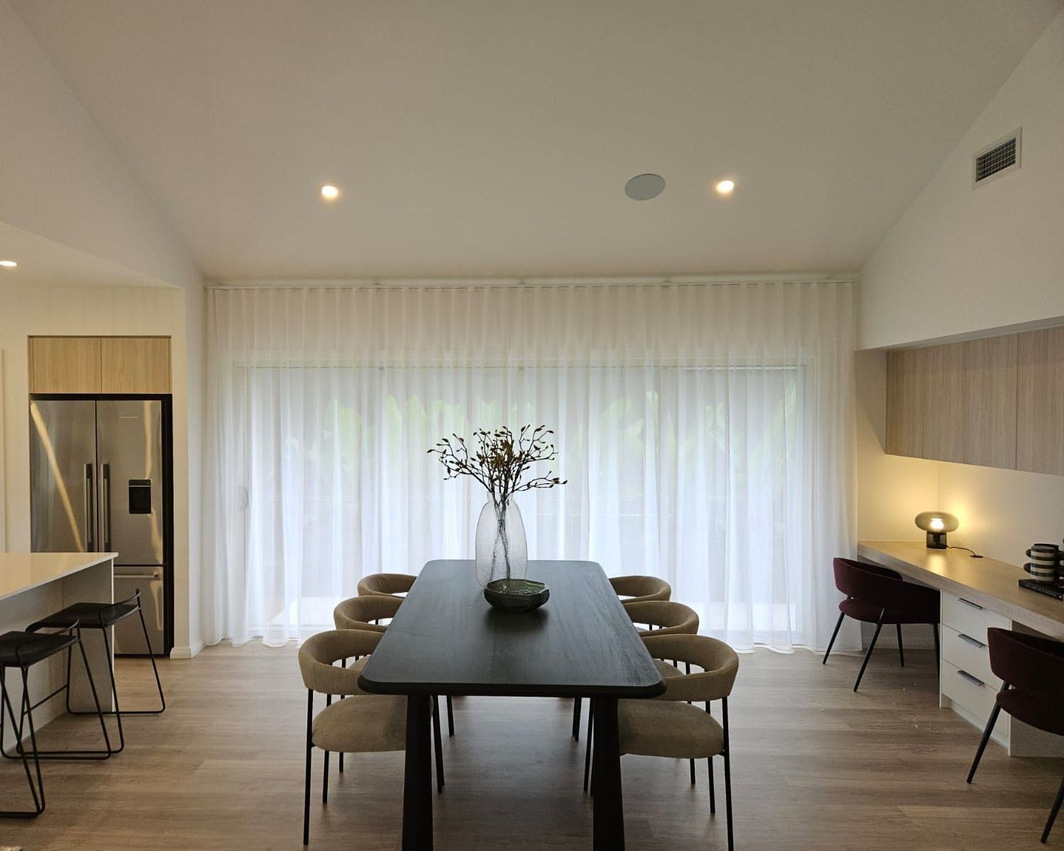 A Dining Room With a Table and Chairs and White Curtains — Bay Blinds & Doors in Bateau Bay, NSW