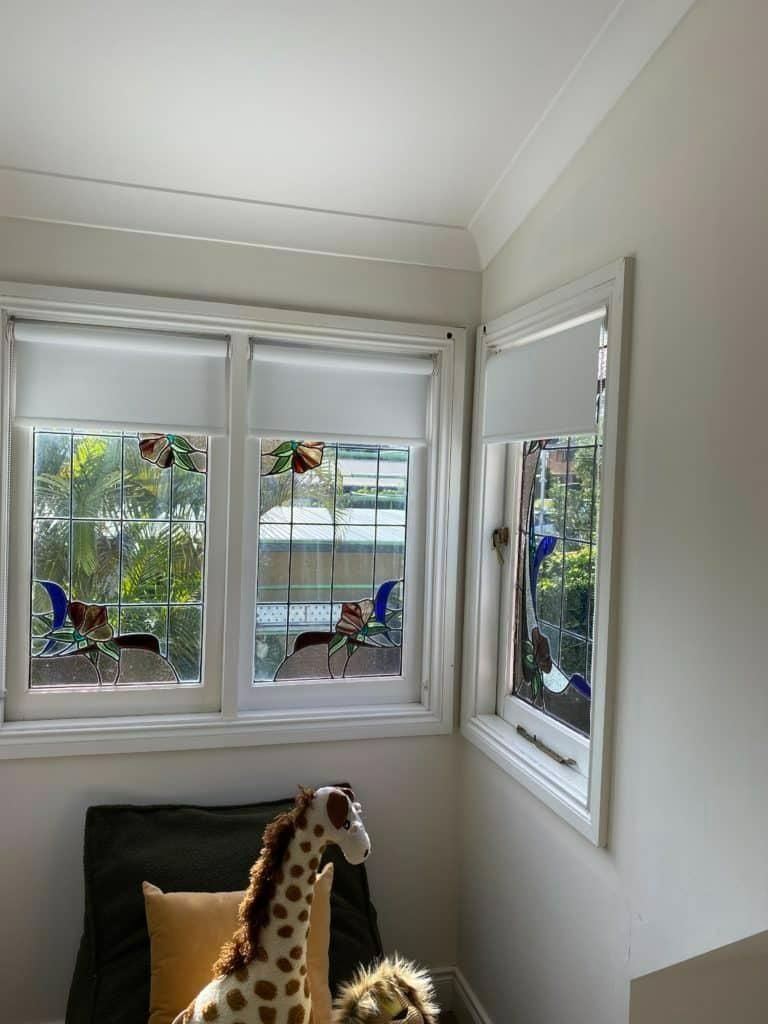 A Gray and White Striped Roman Shade Is Hanging on A Window — Bay Blinds & Doors in Saratoga, NSW