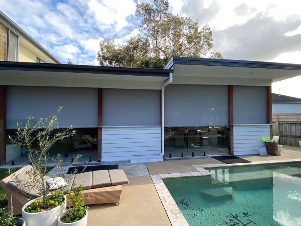 A Cat Is Standing In Front Of A Sliding Glass Door With Blinds — Bay Blinds & Doors in Bateau Bay, NSW