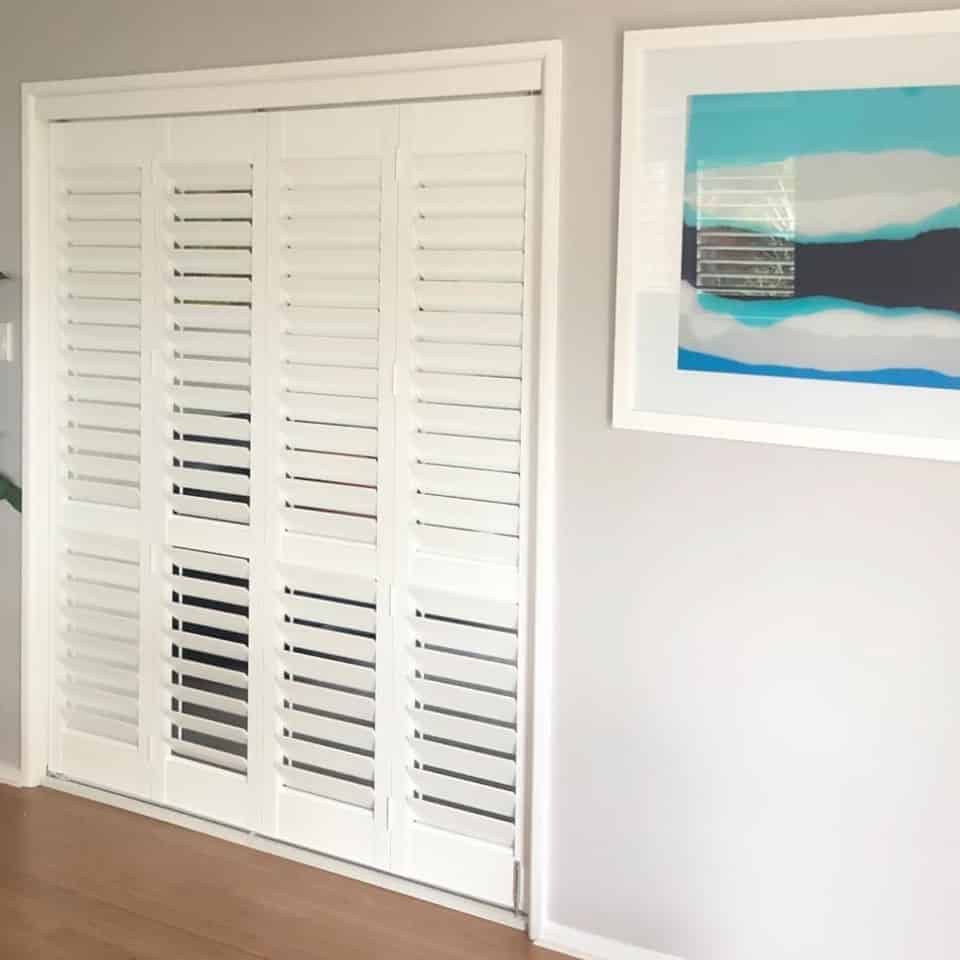 A Balcony With a Couch and Pillows And Shutters on the Windows - Bay Blinds & Doors in Lake Charmhaven, NSW
