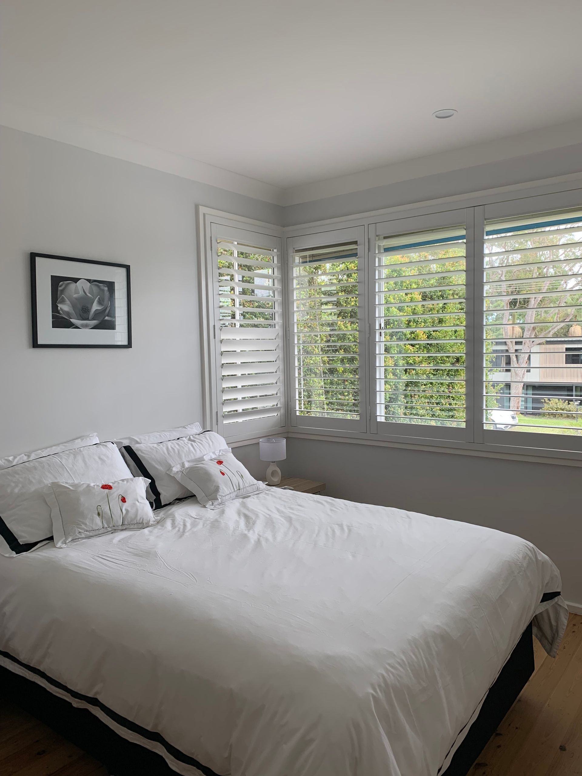 A Balcony with A Couch and Pillows and Shutters on The Windows — Bay Blinds & Doors in Bateau Bay, NSW