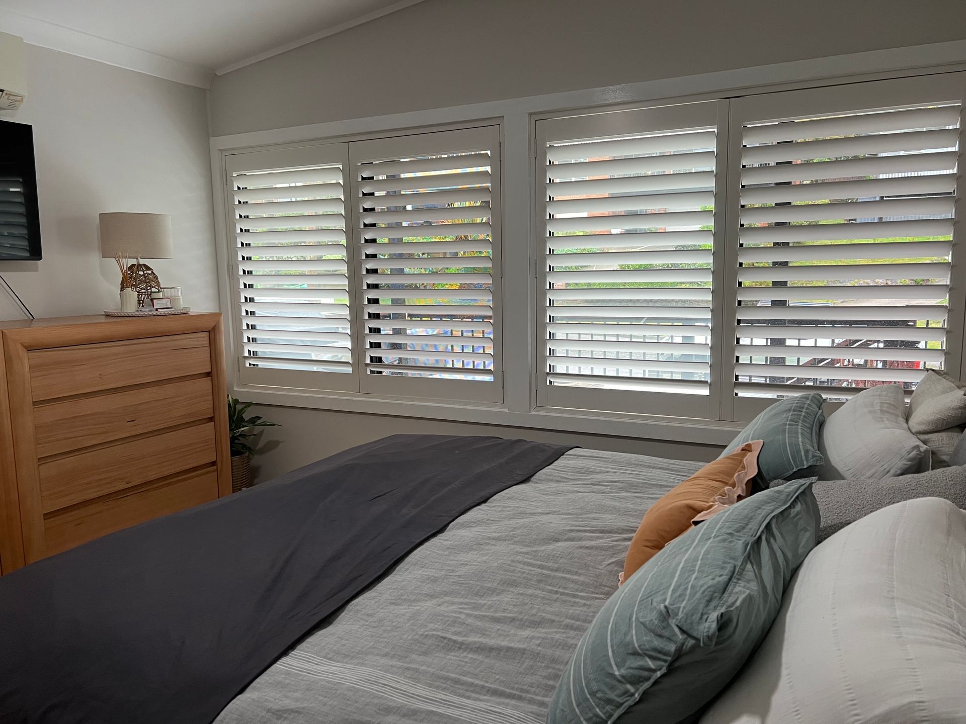 A Balcony with A Couch and Pillows and Shutters on The Windows — Bay Blinds & Doors in Erina, NSW