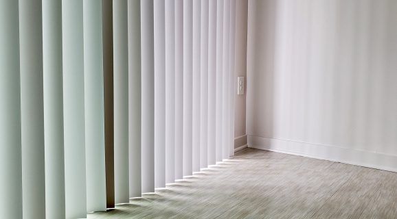 A Gray and White Striped Roman Shade Is Hanging on A Window — Bay Blinds & Doors in Wyee, NSW
