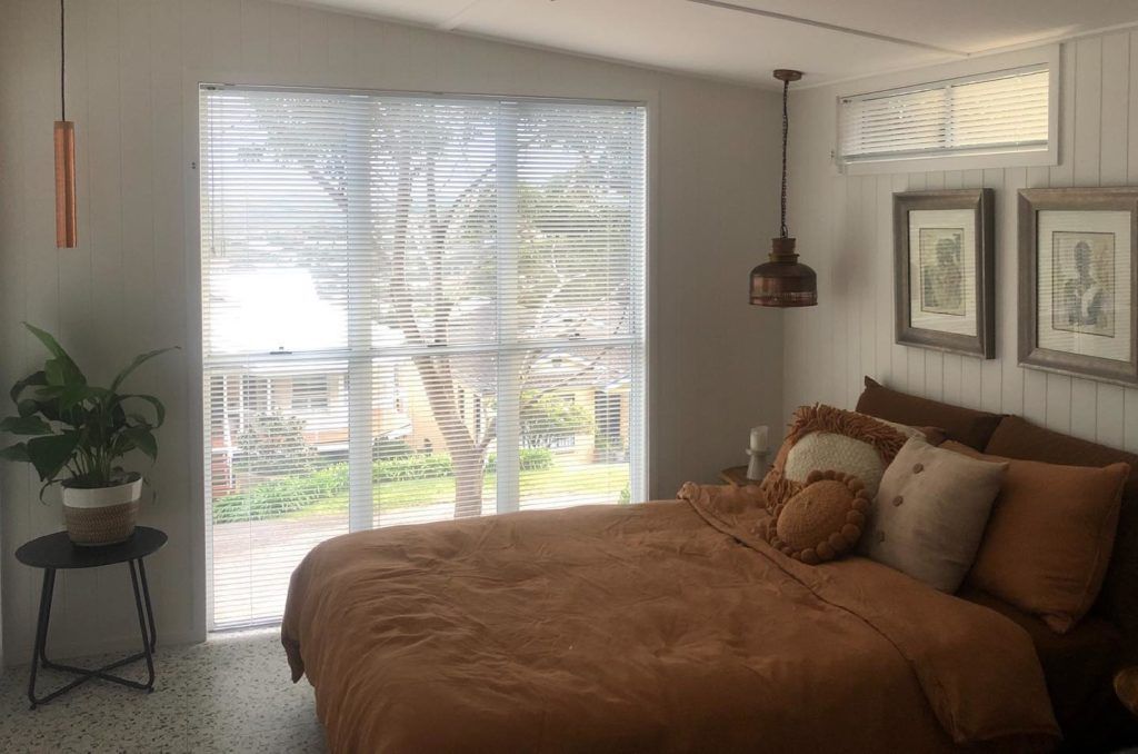 A Gray and White Striped Roman Shade Is Hanging on A Window — Bay Blinds & Doors in Lake Munmorah, NSW