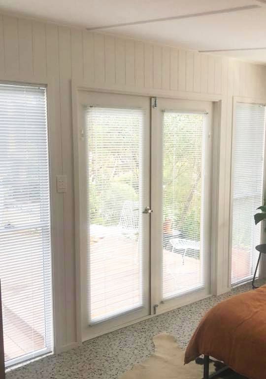 A Bedroom with A Bed and A Window with Shutters — Bay Blinds & Doors in Bateau Bay, NSW
