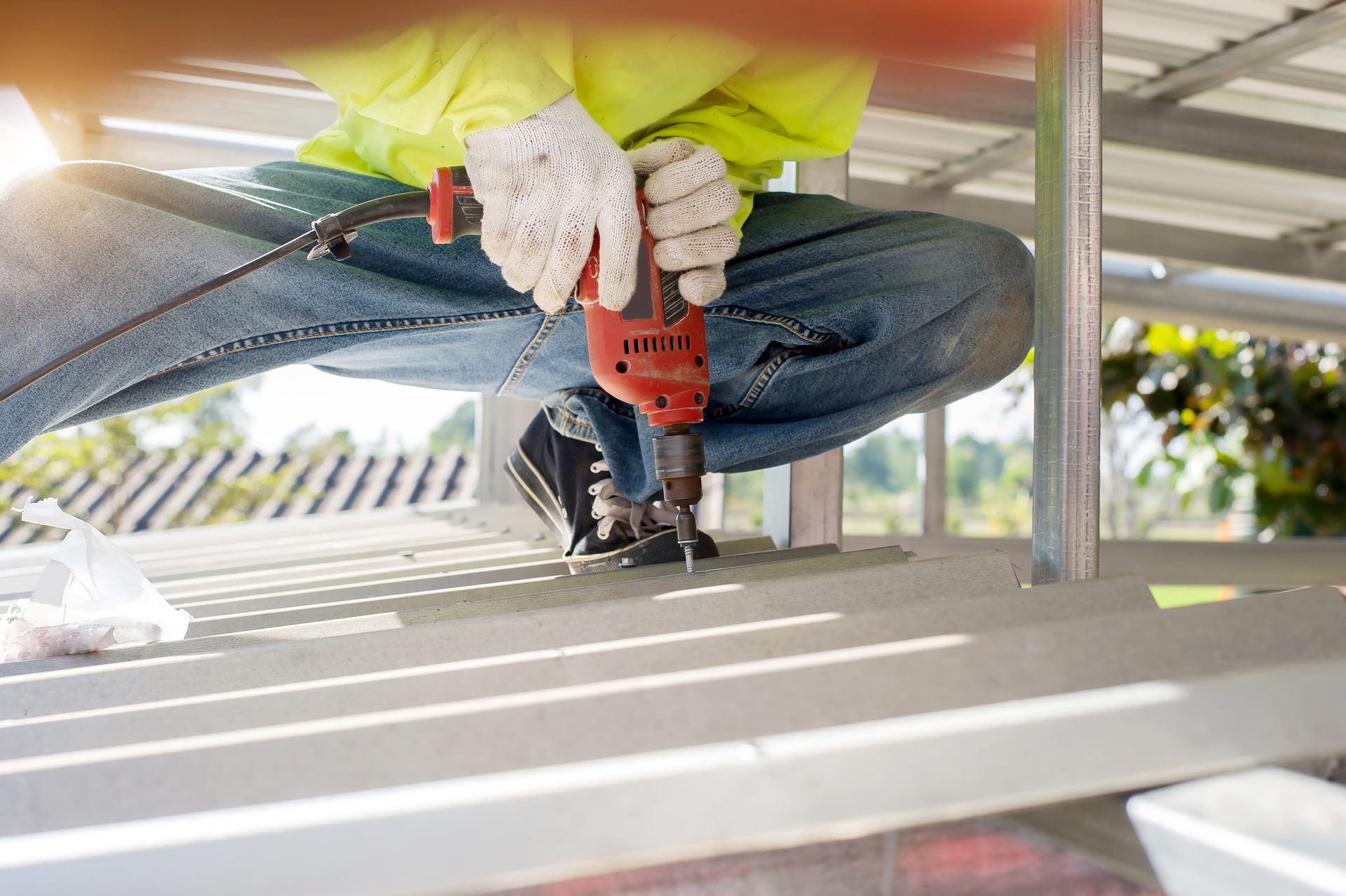 Worker Using a Red Power Drill to Install Boards Under a Structure Outdoors — Geiger Solutions In Bowen Basin, QLD